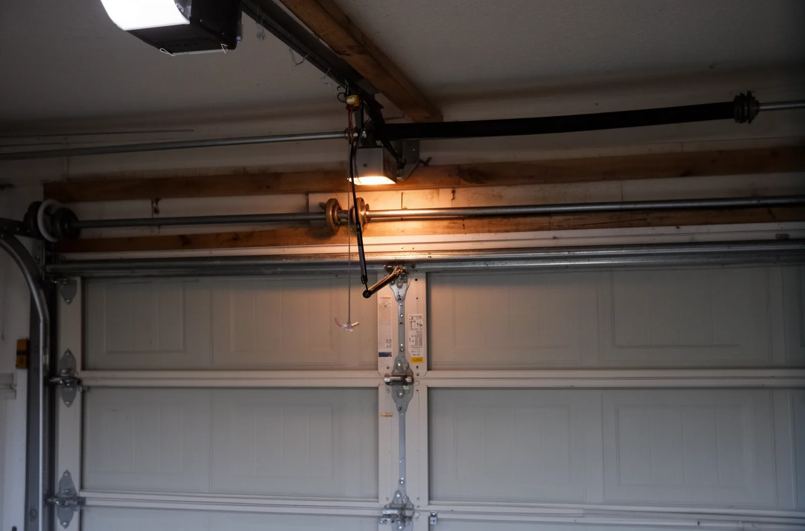 Inside a garage showing door tracks, rollers, and the torsion spring