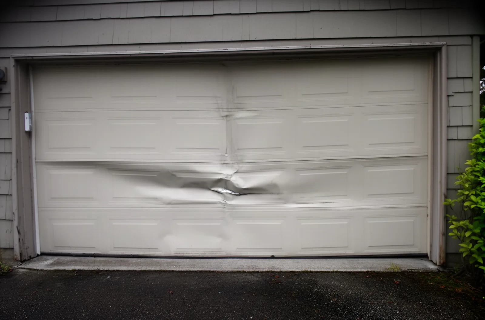 A dented bottom panel on a garage door where a car bumped it