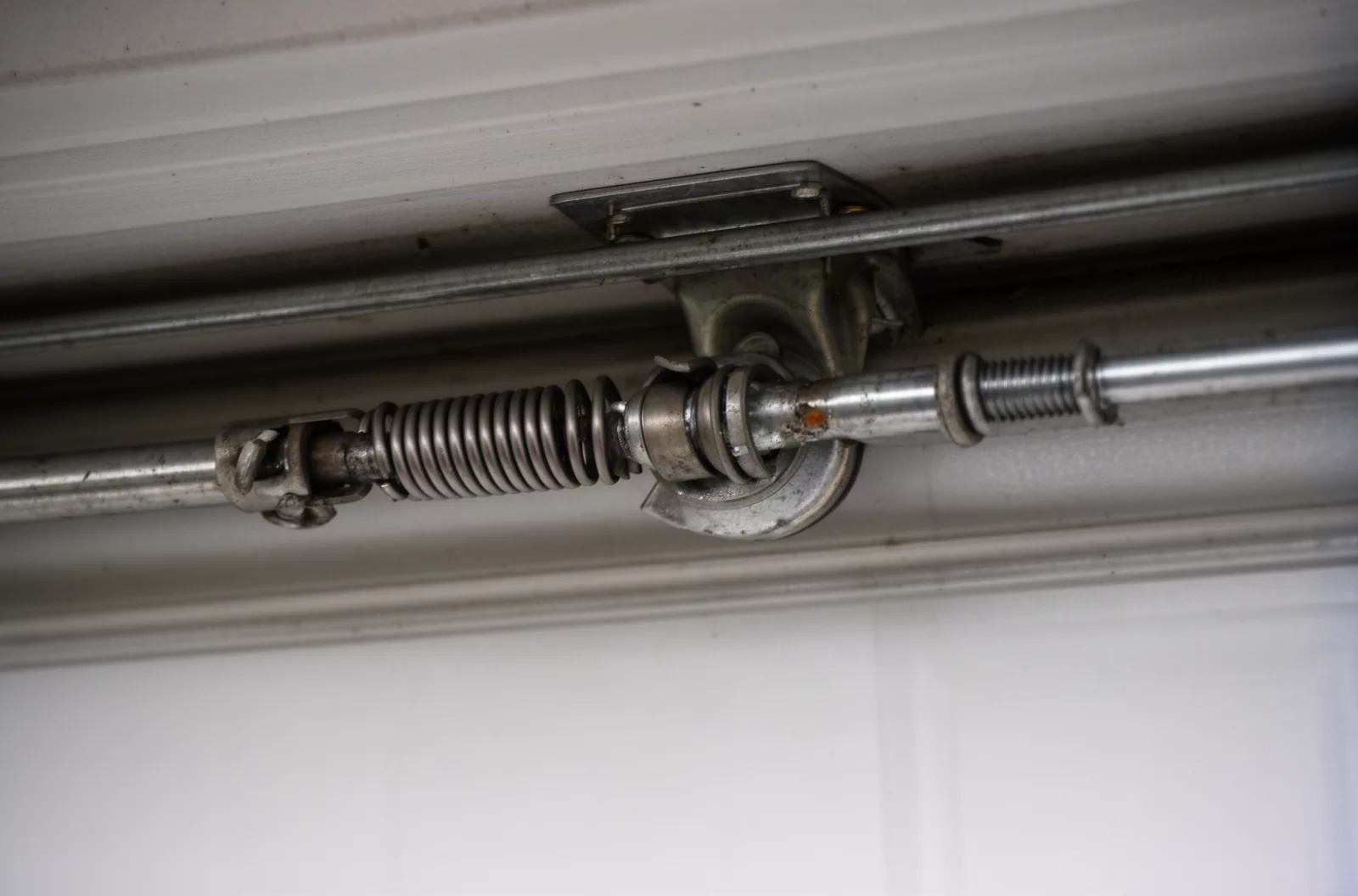 A broken torsion spring with a visible gap in the coil above a garage door